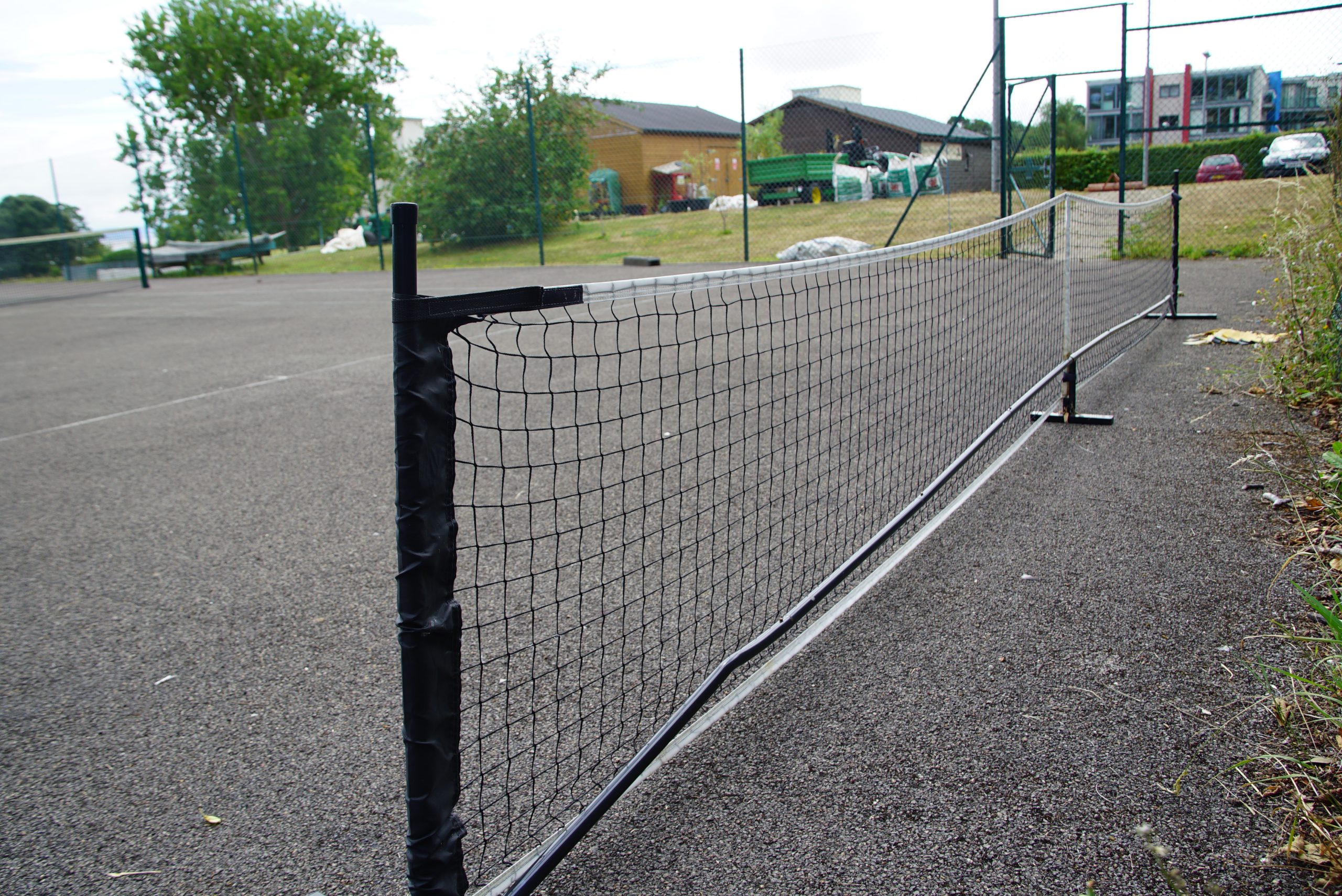 Hayes Point pickleball court with net, paddles, and surrounding greenery, set for resident play.