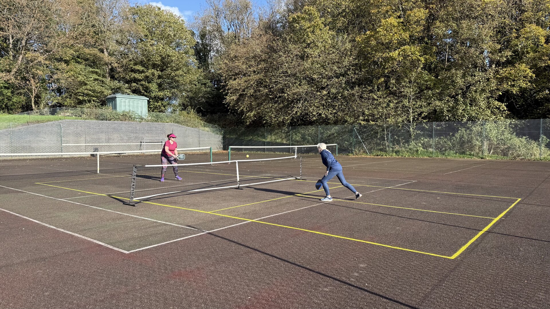 Hayes Point outdoor pickleball court surrounded by trees and greenery, with game in play.